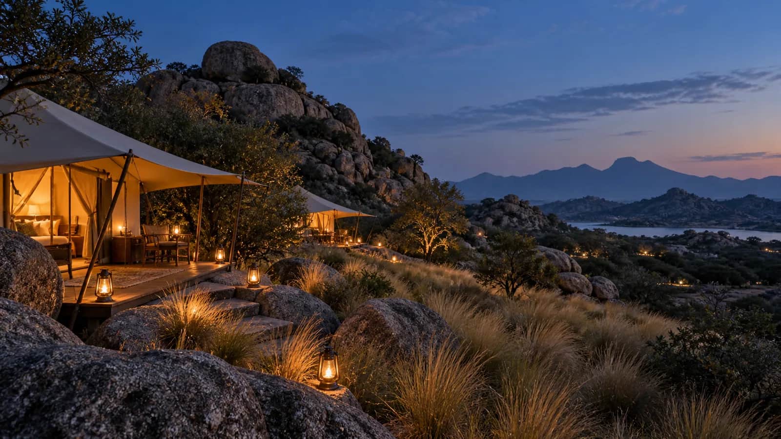 A lantern-lit private tented camp among the granite hills of Jawai at blue hour