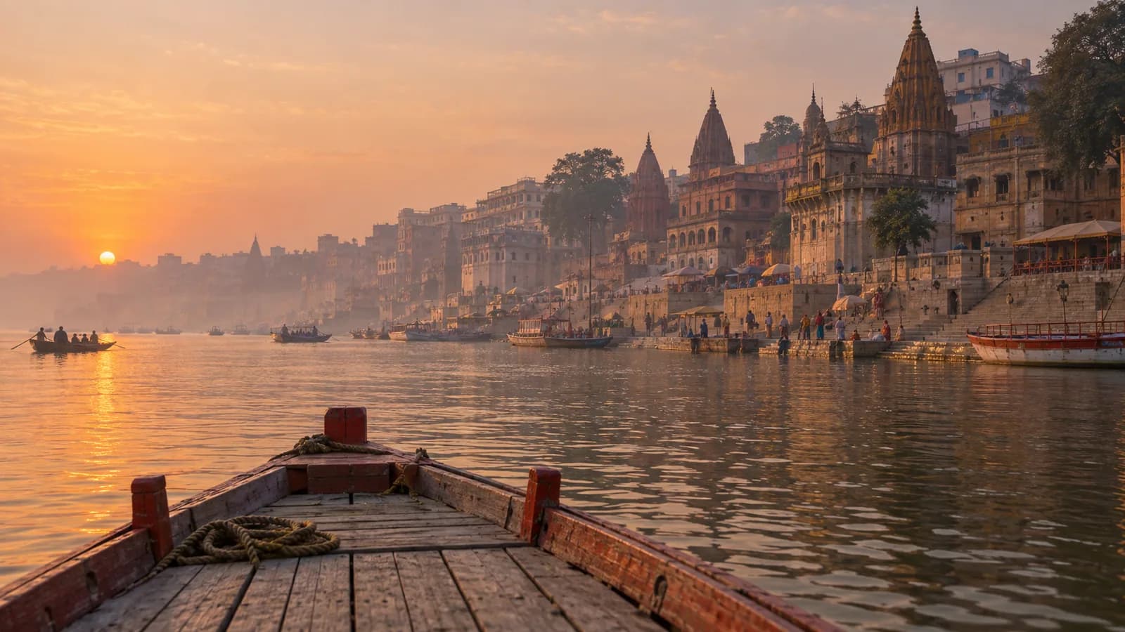 A wooden boat approaching the historic Varanasi ghats on the Ganges at sunrise