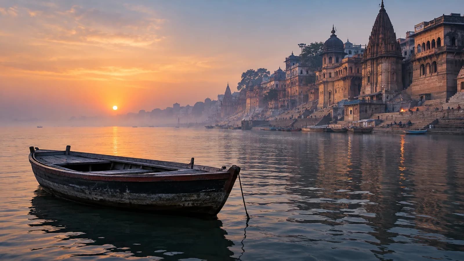 A traditional wooden boat on the Ganges facing Varanasi’s historic ghats at sunrise